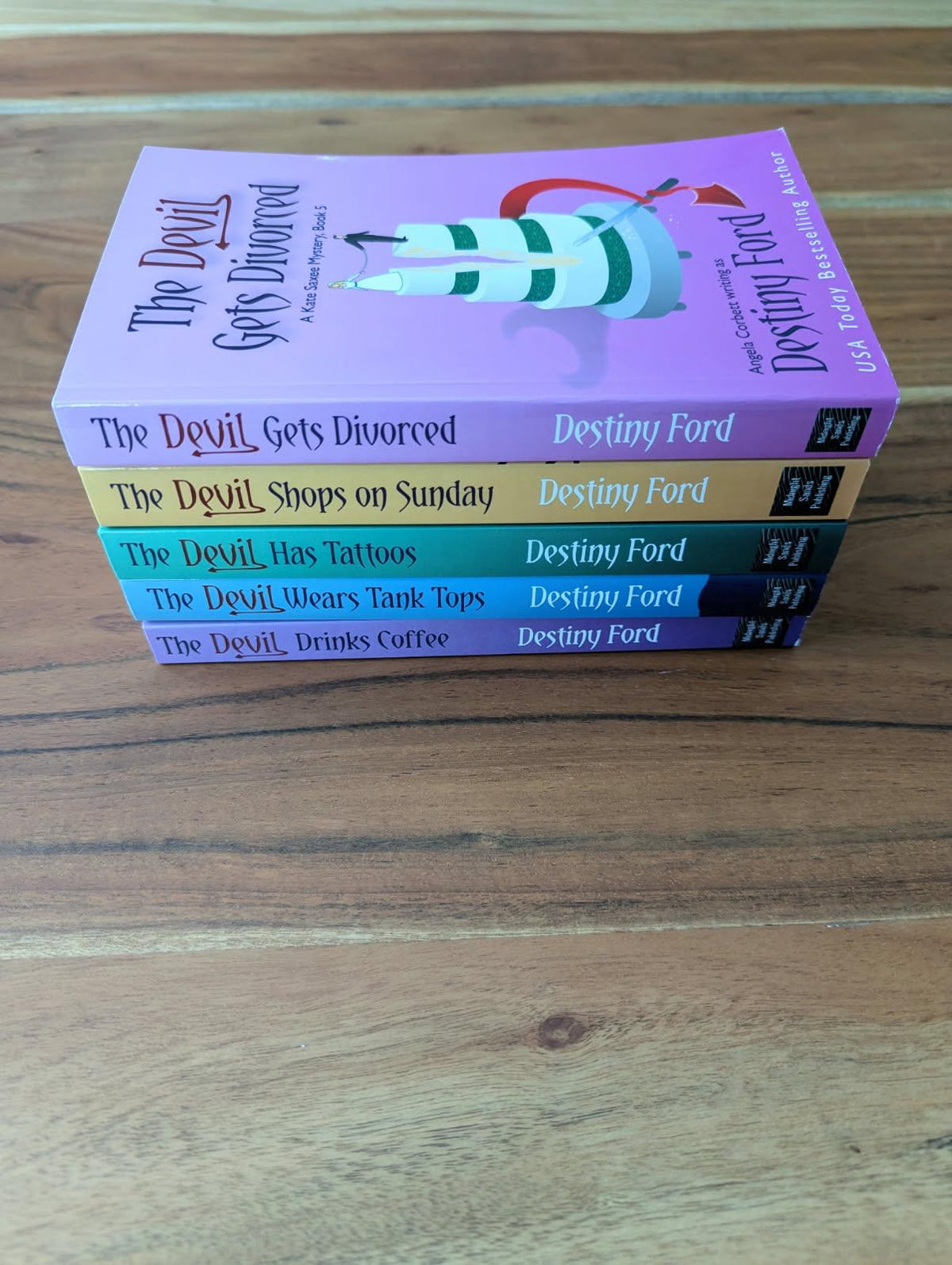 Stack of books titled 'The Devil Gets Divorced' by Destiny Ford on a wooden surface
