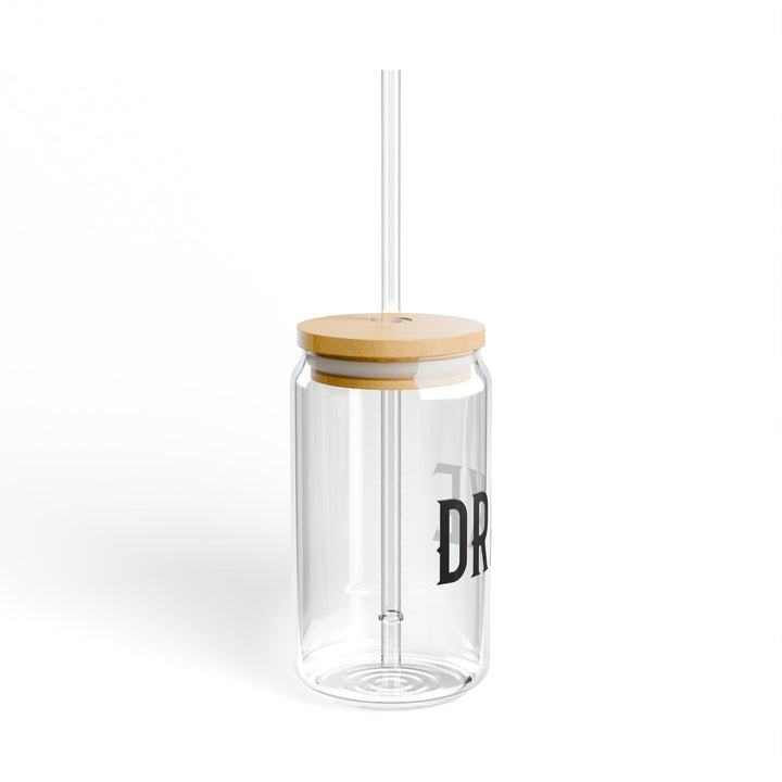 Clear glass tumbler with a wooden lid and straw on a white background