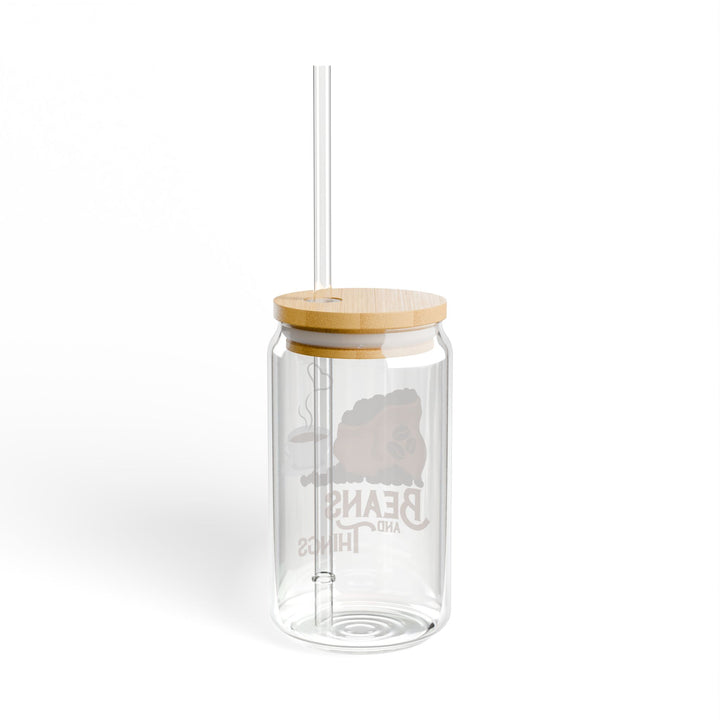 A clear tempered glass sipper with a bamboo lid and a plastic straw, featuring printed text &