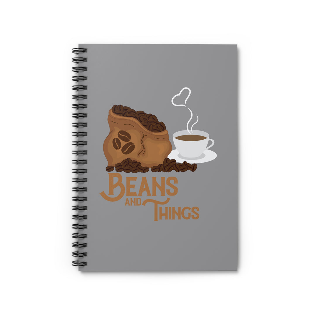 A spiral notebook with a dark grey back cover and a front cover print featuring a stylized design with the text &