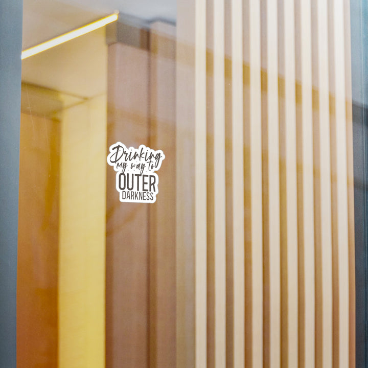A white vinyl sticker with a black text and design, placed on a window.