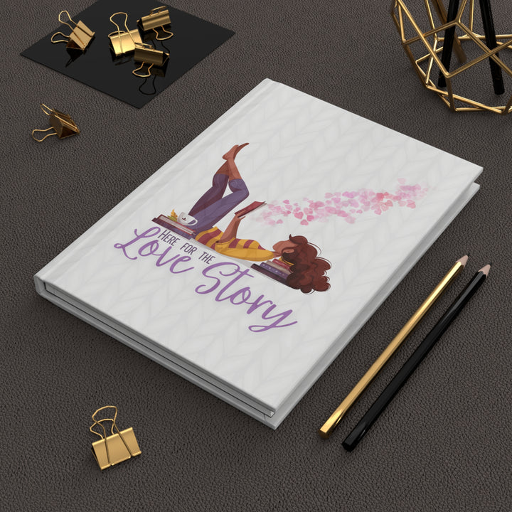 A hardcover journal with a white cover featuring a cartoon illustration of a woman reading a book, with the title &