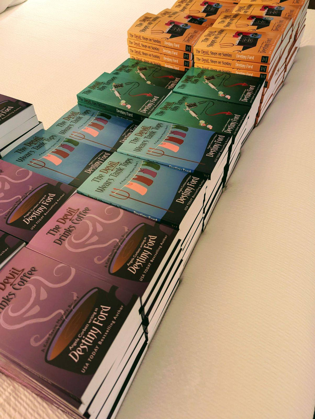 Stacks of paperback books with orange and purple book covers, titled &